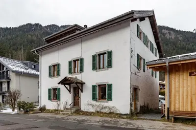 an old white building with green shutters on it at Vouvy - Moderne 4pax Remontee Flegere 5min Praz Arve in Chamonix-Mont-Blanc