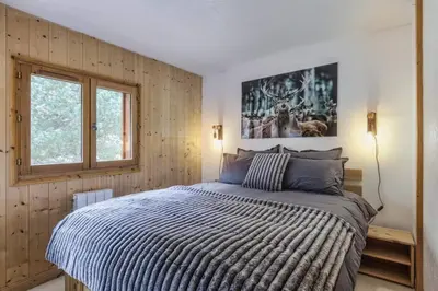 a bedroom with a bed with a striped comforter and a window at Griaz - Cocon 1CH Terrasse Confort Bureau Parking in Les Houches