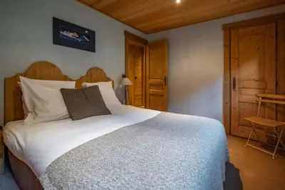 a bedroom with a large white bed with a wooden headboard at Ibex - Chalet 170m2 Cheminee Vue Confort Calme in Les Houches