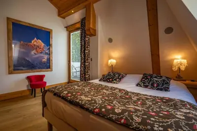 a bedroom with a bed and a red chair at Astoria - UltraCentral 140m2 Balcons Vues Balneo Sauna in Chamonix-Mont-Blanc