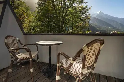 two chairs and a table on a balcony with a view at Astoria - UltraCentral 140m2 Balcons Vues Balneo Sauna in Chamonix-Mont-Blanc