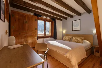 a bedroom with a bed and a table and a window at Cyclamens - Cosy Chalet 500m Flegere Cheminee Vue Garage in Chamonix-Mont-Blanc