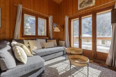 a living room with a couch and some windows at Cyclamens - Cosy Chalet 500m Flegere Cheminee Vue Garage in Chamonix-Mont-Blanc