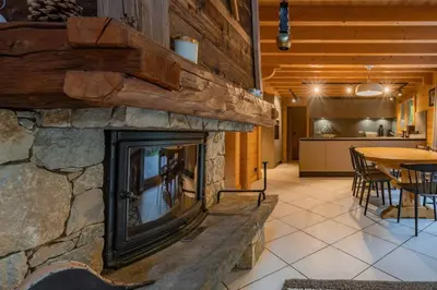 a stone fireplace in a living room with a table at Glaciers Chalet Cheminee Vue Confort Calme in Les Houches