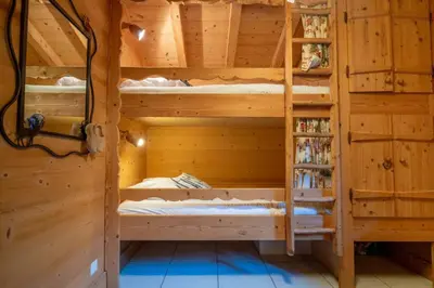a room with bunk beds in a wooden house at Glaciers Chalet Cheminee Vue Confort Calme in Les Houches