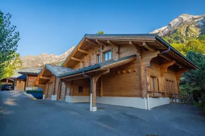 a large wooden cabin with mountains in the background at Glaciers Chalet Cheminee Vue Confort Calme in Les Houches