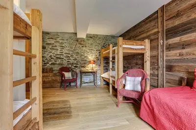 a bedroom with two bunk beds and a table at Gublin - Apart Famille Vue360 Nature Calme Cheminee in Les Houches
