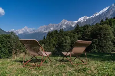 two chairs sitting in a field with mountains in the background at Gublin - Apart Famille Vue360 Nature Calme Cheminee in Les Houches