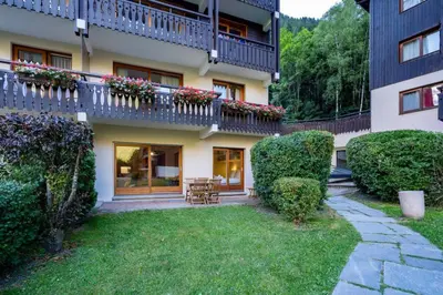 an apartment building with a patio and a yard at Mummery - Central T2 Pied piste Vue Parking Terrasse in Chamonix-Mont-Blanc