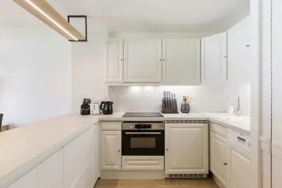 a white kitchen with white cabinets and a stove top oven at Mummery - Central T2 Pied piste Vue Parking Terrasse in Chamonix-Mont-Blanc