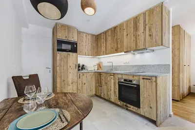 a kitchen with wooden cabinets and a wooden table with wine glasses at Balmat - UltraCentral 2pax Confort Vue Quartier Vivant in Chamonix-Mont-Blanc
