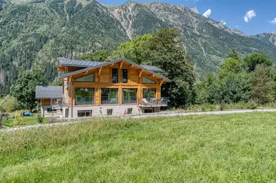 a large wooden house with mountains in the background at Couchant Chalet Lumineux 6pax Vues Terrasses Confort in Chamonix-Mont-Blanc
