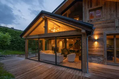 a glass house with a living room and a deck at Eden Chalet Spacieux Vues Jacuzzi Cheminee BBQ in Chamonix-Mont-Blanc