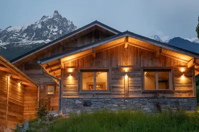 a log cabin with a mountain in the background at Eden Chalet Spacieux Vues Jacuzzi Cheminee BBQ in Chamonix-Mont-Blanc