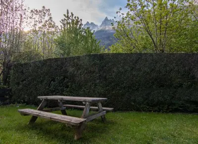 a picnic table sitting in the grass next to a hedge at Sapi Cocon 4pax Centre Jardin Remontees TV Wifi in Chamonix-Mont-Blanc