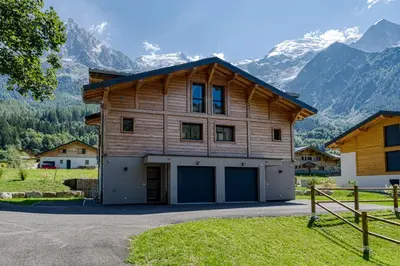 a large wooden house with mountains in the background at Levant Chalet Moderne 6pax Vues Terrasses Confort in Chamonix-Mont-Blanc
