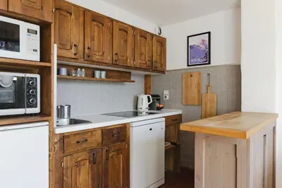 a kitchen with wooden cabinets and a white microwave at Argentero Cosy Duplex Pied Pistes Vue Grands Montets in Chamonix-Mont-Blanc