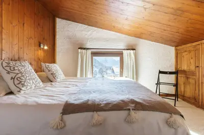 a large bed in a room with a window at Argentero Cosy Duplex Pied Pistes Vue Grands Montets in Chamonix-Mont-Blanc