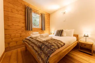 a bedroom with a bed with wooden walls and a window at Etoile Cosy Balcon Vue Montagne Proche Centre in Chamonix-Mont-Blanc
