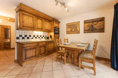 a kitchen with wooden cabinets and a table and chairs at Etoile Cosy Balcon Vue Montagne Proche Centre in Chamonix-Mont-Blanc
