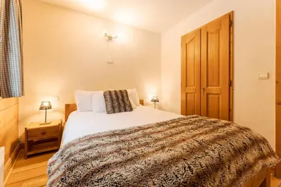 a bedroom with a bed and a wooden door at Etoile Cosy Balcon Vue Montagne Proche Centre in Chamonix-Mont-Blanc