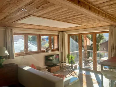 a living room with a couch and a tv and windows at Chalet Sablod in Les Contamines-Montjoie