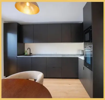 a kitchen with black cabinets and a wooden table at Le Balcon du Mont-BIanc I Duplex I Combloux in Combloux