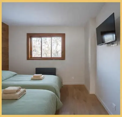 two beds in a room with a tv and a window at Le Balcon du Mont-BIanc I Duplex I Combloux in Combloux