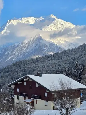 a house with a snow covered mountain in the background at Cocon Saint-Gervais in Saint-Gervais-les-Bains