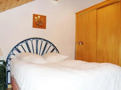 a bedroom with a bed with white sheets and a wooden door at Duplex à Samoëns, 6 pers, balcon sud, parking - FR-1-815-48 in Samoëns