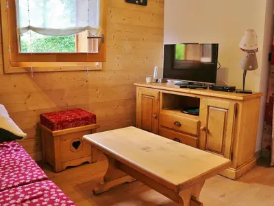 a living room with a tv on a wooden cabinet with a table at Appartement neuf 3 pièces - 6 pers - Vue montagne - FR-1-815-49 in Samoëns