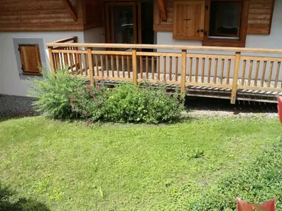 a wooden porch of a house with some flowers at Appartement neuf 3 pièces - 6 pers - Vue montagne - FR-1-815-49 in Samoëns