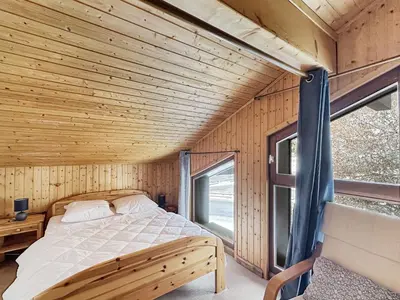 a bed in a wooden room with a window at ES117 - Duplex 6 pers pied de pistes in Les Carroz d'Araches