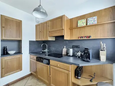a kitchen with wooden cabinets and a black counter top at ES117 - Duplex 6 pers pied de pistes in Les Carroz d'Araches