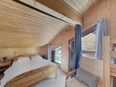 a bed in a wooden room with a window at ES117 - Duplex 6 pers pied de pistes in Les Carroz d'Araches