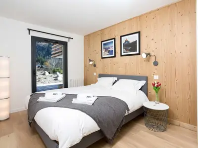 a bedroom with a large bed with a wooden wall at Apartment La Cordee 504 mit Terrasse by Interhome in Chamonix-Mont-Blanc