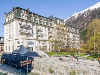 a large white building next to a body of water at Apartment Wohnung in Chamonix by Interhome in Chamonix-Mont-Blanc