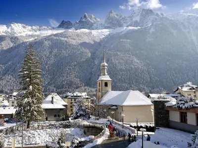 a snowy village with a church and mountains in the background at Apartment Ginabelle 8 Wohnung by Interhome in Chamonix-Mont-Blanc