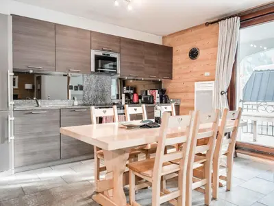 a kitchen with a wooden table and chairs at Apartment Wohnung in Chamonix mit sonnigem Balkon und toller Aussicht by Interhome in Chamonix-Mont-Blanc