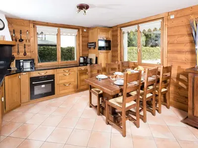 a kitchen with wooden cabinets and a wooden table and chairs at Apartment Komfortable Wohnung in Chamonix mit Südterrasse by Interhome in Chamonix-Mont-Blanc
