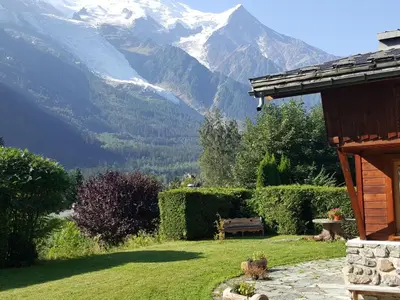 a garden with a bench and mountains in the background at Holiday Home Chalet Martinique by Interhome in Chamonix-Mont-Blanc