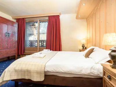 a bedroom with a large bed with red curtains at Apartment Chamois Apartment by Interhome in Chamonix-Mont-Blanc