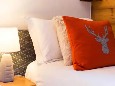 a bed with an orange pillow with a deer on it at Apartment in Chamonix mit geräumigem Balkon und weitem Blick by Interhome in Chamonix-Mont-Blanc