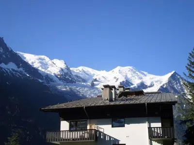 a building with snow covered mountains in the background at Apartment Le Brevent Wohnung by Interhome in Chamonix-Mont-Blanc