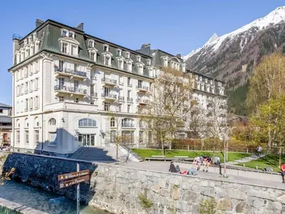 a large white building next to a body of water at Apartment Wohnung in Chamonix Centre-Ville und Bergblick by Interhome in Chamonix-Mont-Blanc