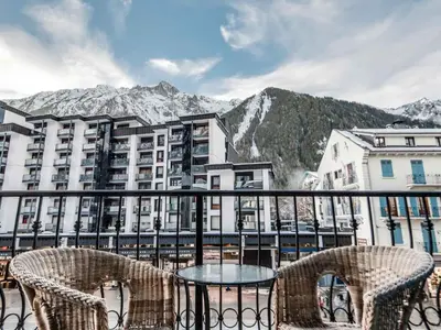a table and chairs on a balcony with mountains at Apartment Balmat Wohnung by Interhome in Chamonix-Mont-Blanc