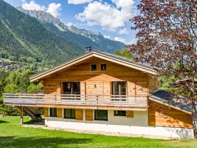 a wooden house with a large balcony in the mountains at Holiday Home Chalet de l'Ours - Bärenhütte by Interhome in Chamonix-Mont-Blanc