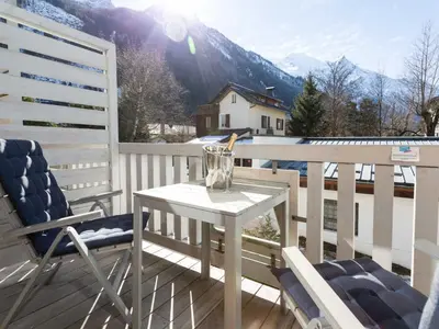a white table and chairs on a balcony with mountains at Apartment Wohnung Sauberands 18 mit Balkon by Interhome in Chamonix-Mont-Blanc