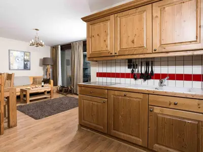 a kitchen with wooden cabinets and a living room at Apartment Le Paradis 8 Wohnung by Interhome in Chamonix-Mont-Blanc