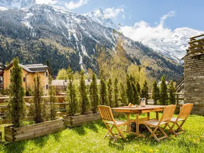 a table and chairs on a lawn with mountains in the background at Apartment Apothekerwohnung by Interhome in Chamonix-Mont-Blanc